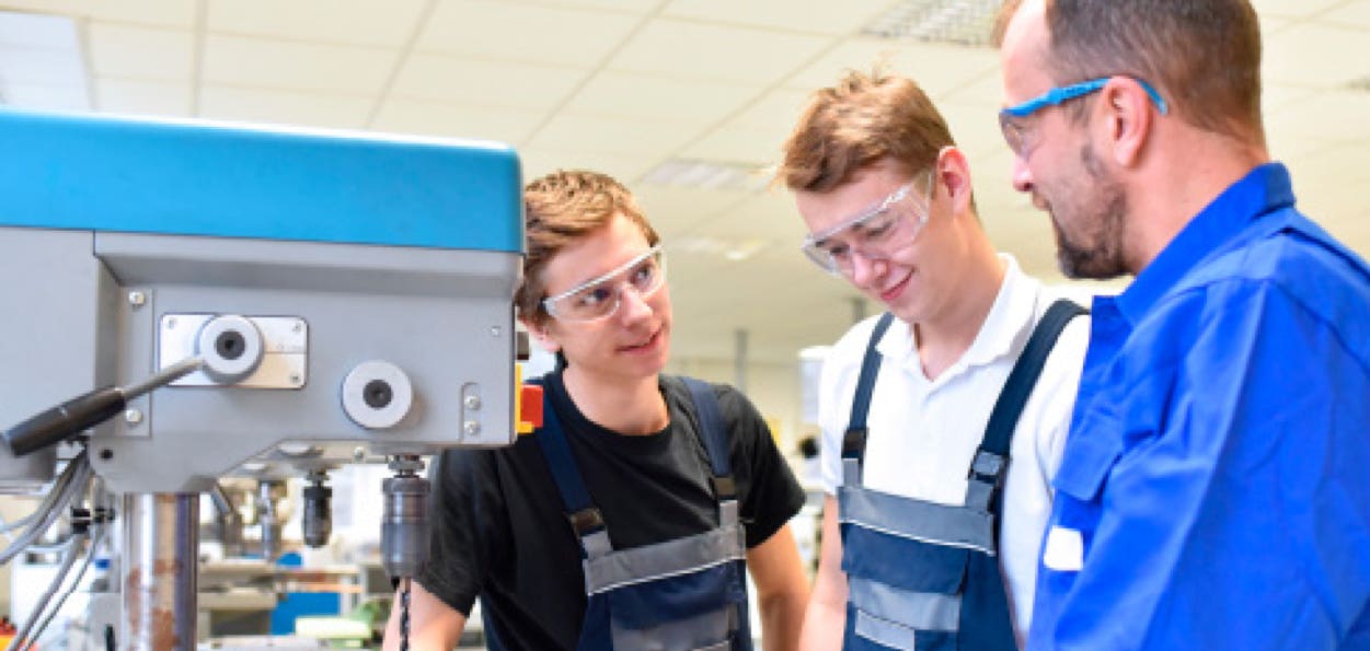 Schüler mit Meister an einer Maschine